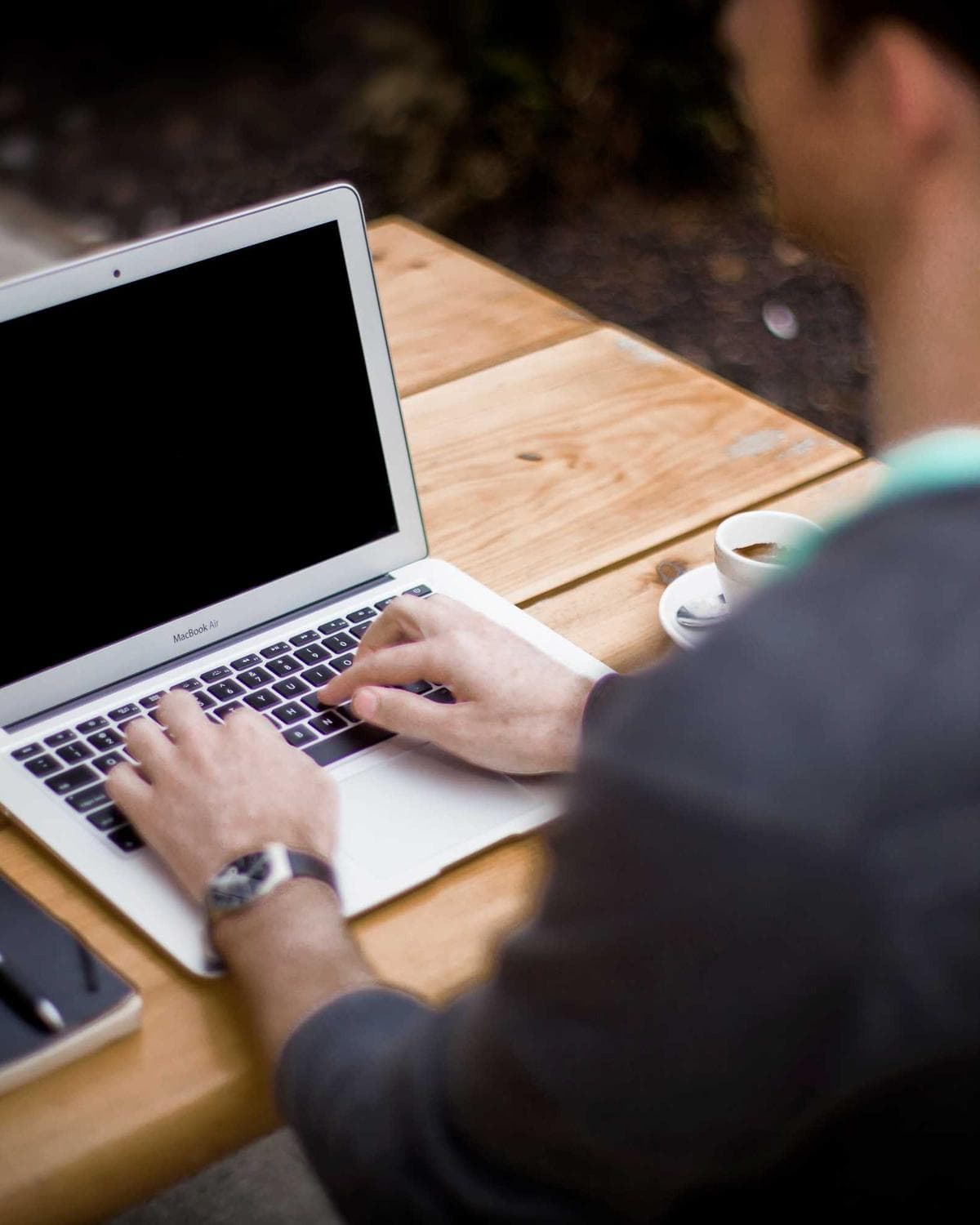 Placeholder photograph of someone working at a laptop at a wooden table.